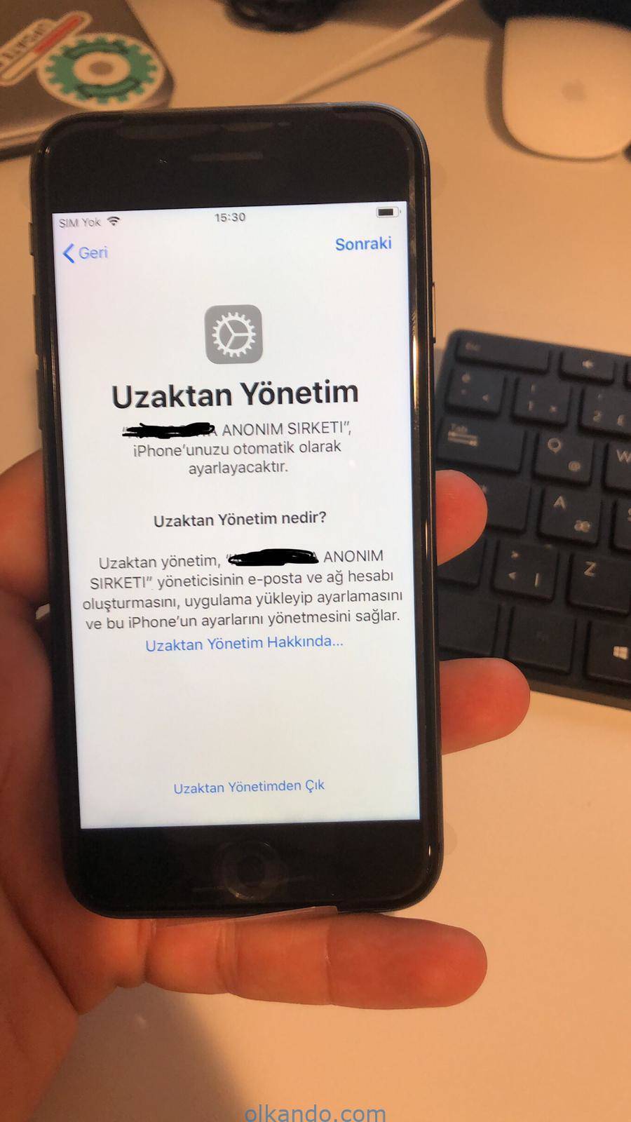 Elde tutulan iPhone ekranında "Uzaktan Yönetim" karşılama sayfası. Kurumun iPhone'u otomatik ayarlayacağı ve yöneticinin hesap oluşturup uygulama yükleyebileceği açıklanıyor.
